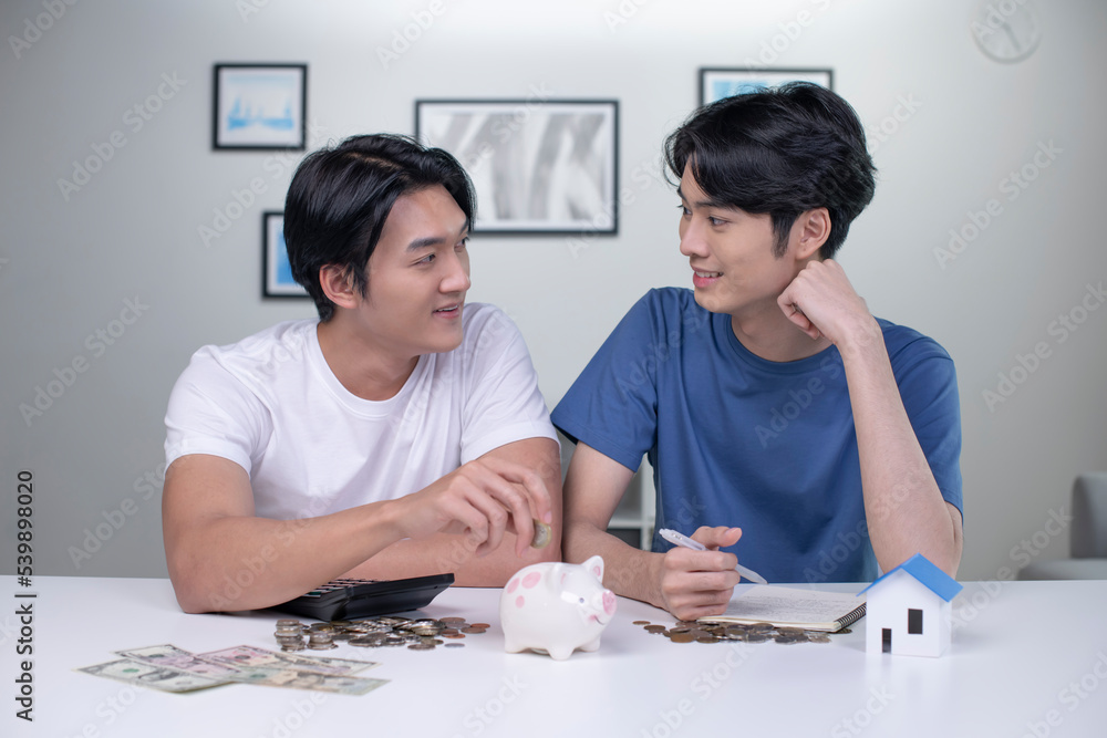 Young happy Asian gay couple saving money to buy a house. LGBT men couple saving money for family and home. Young happy Asian gay couple saving money to buy a house. LGBT men couple saving money for family and home.