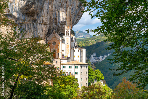 Fotografie, Obraz View from the mountain hiking trail of the Santuario de la Madonna della Corona, a picturesque historic mountainside church built in 1625 in Spiazzi, Italy