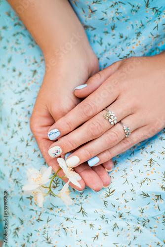 Female hands with flower on floral blue background