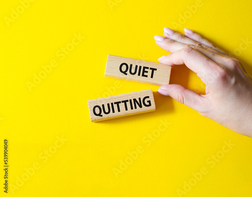 Quiet quitting symbol. Concept word Quiet quitting on wooden blocks. Beautiful yellow background. Businessman hand. Business and Quiet quitting concept. Copy space.