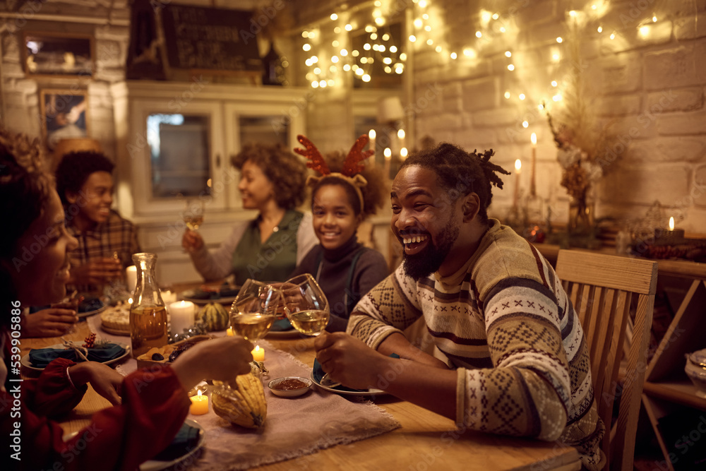 Happy black couple toasting while celebrating Thanksgiving with their family at dining table. Happy black couple toasting while celebrating Thanksgiving with their family at dining table.