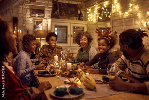 Happy black extended family talking at dining table while celebrating Thanksgiving together.