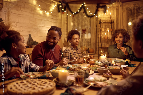 Happy African American extended family talking during Thanksgiving dinner at dining table.