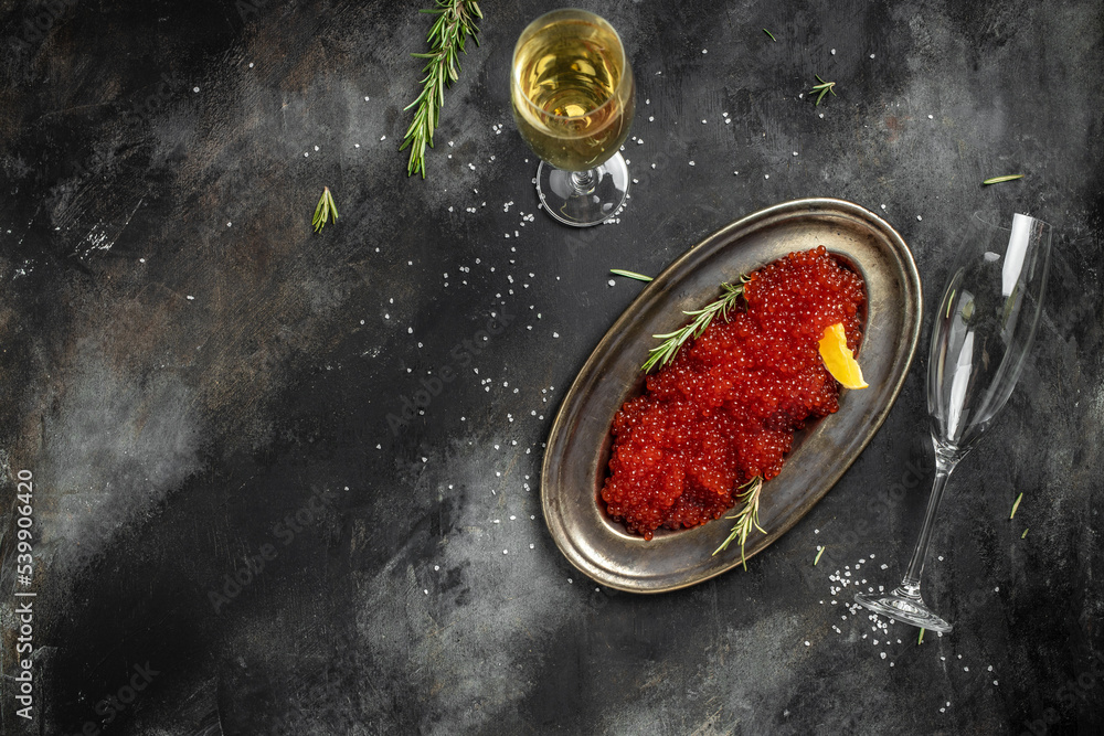 Caviar. delicious red caviar in vintage plate and champagne on dark background. banner, menu, recipe. selective focus, place for text