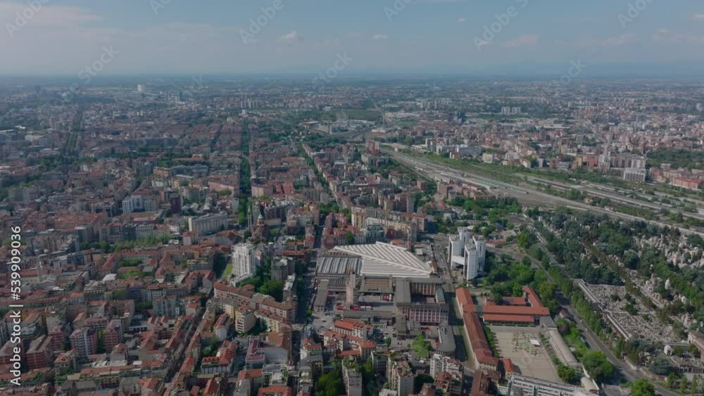 Aerial panoramic shot of large city. Apartment buildings in residential boroughs, cemetery and railway transport infrastructure. Milano, Italy Aerial panoramic shot of large city. Apartment buildings in residential boroughs, cemetery and railway transport infrastructure. Milano, Italy