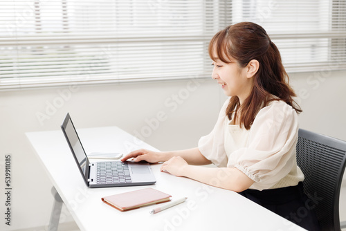 オフィスやレンタルスペースでパソコンを操作する女性。オンラインで快適に仕事をするイメージ。 photo