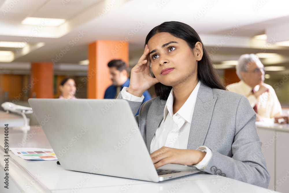 Thoughtful millennial professional solving problems using laptop in office. Thoughtful millennial professional solving problems using laptop in office.