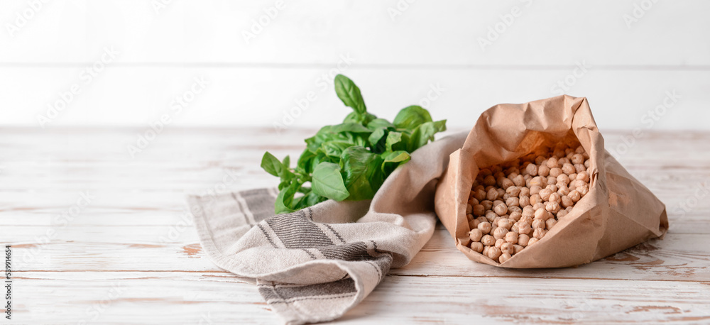 Paper bag with raw chickpea on wooden table