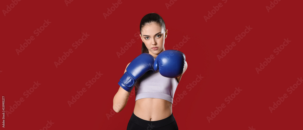 Sporty female coach in boxing gloves on red background Sporty female coach in boxing gloves on red background