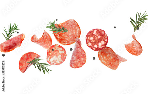 Flying slices of delicious salami and spices isolated on white photo