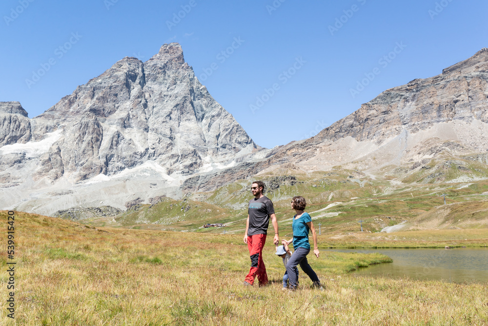 Couple with her little daughter doing a hike trail around Matterhorn in Cervinia, Italy. 