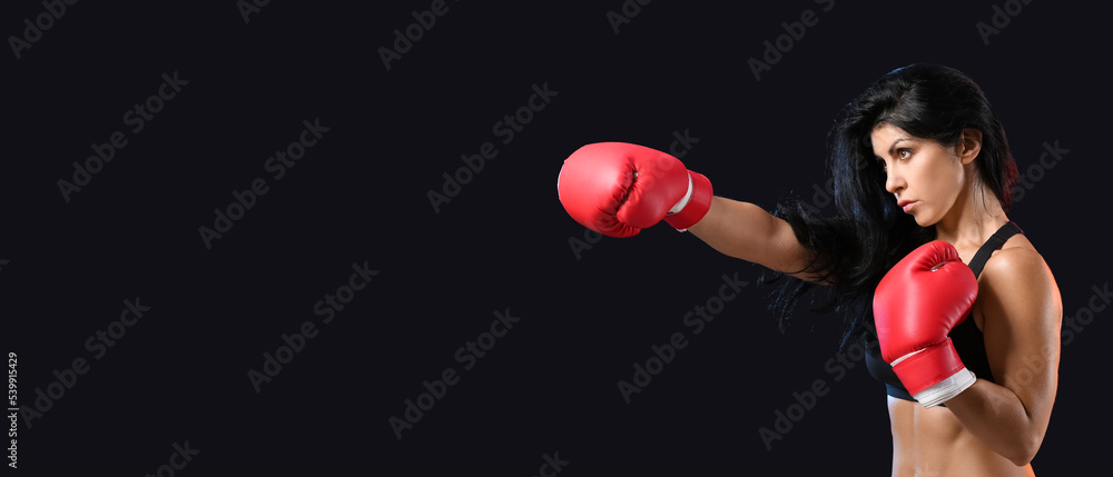 Sporty female boxer on dark background with space for text