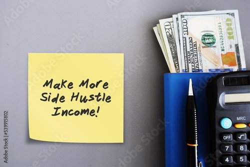 Cash dollars money, calculator ,pen, blue notebook, on grey background, with note written MAKE MORE SIDE HUSTLE INCOME ,concept of financial planning, make more money from side job or side gig