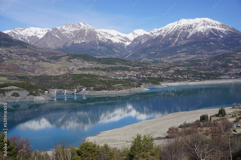 mirror reflection of the mountains on a clear spring day in Serre Ponçon lake in the Southern Alps, France 