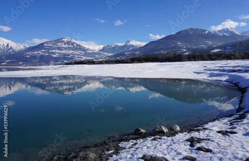 mirror reflection of the mountains in winter at Serre Ponçon lake in the Southern Alps, France 