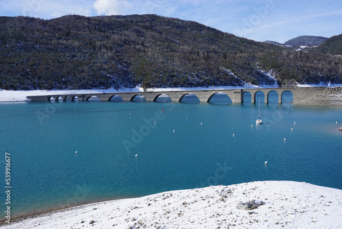old stone bridge of Serre Ponçon lake in the Southern Alps, France on a clear winter day half submerged in the Bay de Chanteloupe