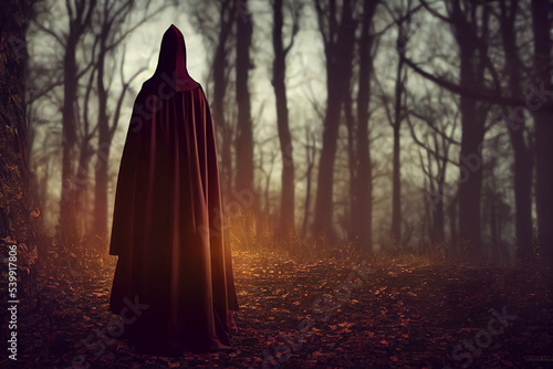 Witch woman in black dress with hood in a dark autumn forest, Halloween theme