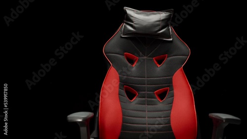 The black and red gaming computer chair rotates on a black background. photo