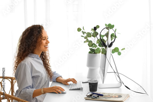 Young African-American woman working with computer at table in office
