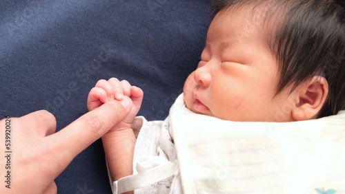 産後1か月0歳の新生児が大人の指を握っている右寄りの写真 photo