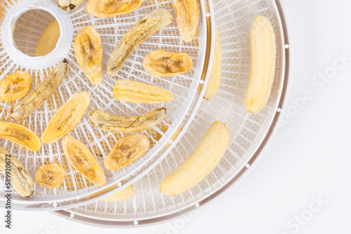 on a round white grill  dried sliced and whole peeled banana  close-up