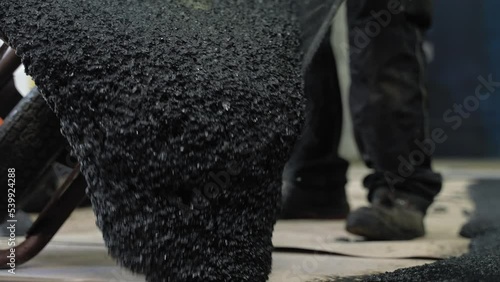Worker dumping the tar from the wheelbarrow on the surface where he is working