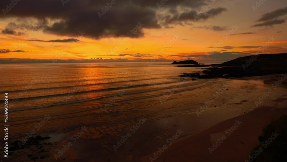 Cinemagraph seamless video loop of a calm sunset evening seaside beach close to St Ives in Cornwall, England, UK. Red and orange sky, soft waves and a lighthouse. Wide panoramic view. Romantic tourism Cinemagraph seamless video loop of a calm sunset evening seaside beach close to St Ives in Cornwall, England, UK. Red and orange sky, soft waves and a lighthouse. Wide panoramic view. Romantic tourism