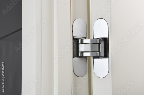 Photography New modern metal door hinges hidden on white wooden doors.
