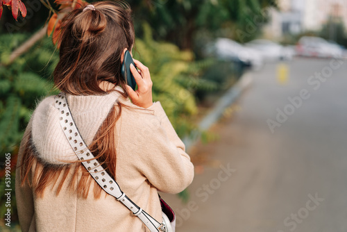 Woman talking on smartphone, back view, with space for text or design concepts.