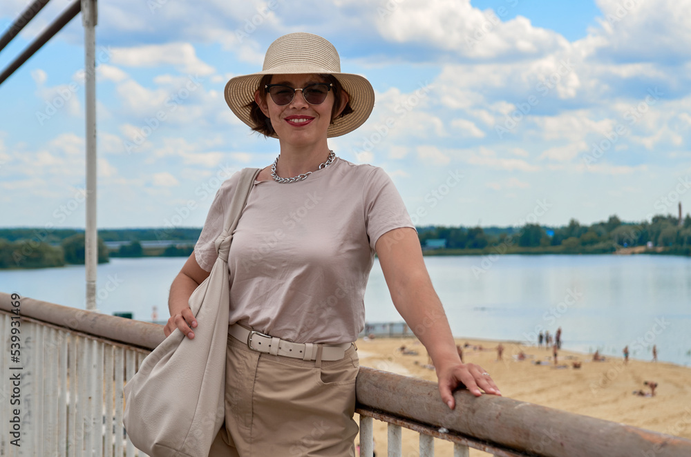 Portrait of travelling woman in hat against the backdrop of the river and city