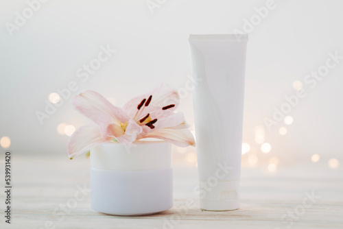 Beauty products bottles with garland lights and flowers. Holiday gift cosmetic concept