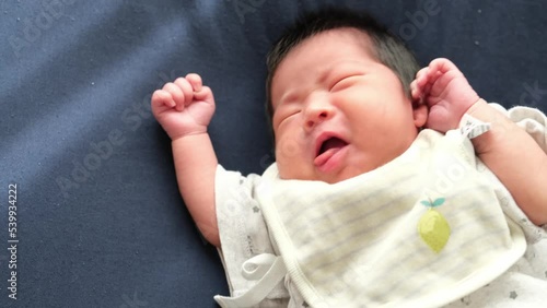 布団の上で寝ているときにあくびをする産後1か月の0歳新生児の赤ちゃんの動画 photo
