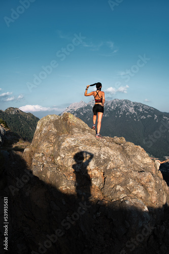 Shadow of a photographer portraying a sportswoman on a rock