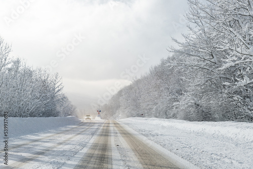 Scenic view of car alone car on curve turn beautiful mountain forest cpuntry woods highway road at cold snowy sunny weather winter day. Wintry frosty route landcape. Travel season journey trip drive