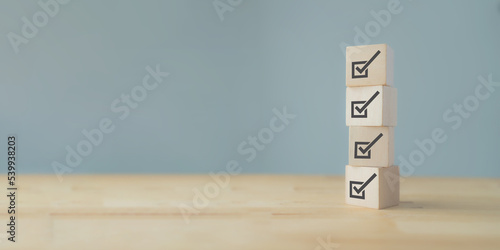 Corporate regulatory and compliance. Quality control management, ISO certification. Product, service quality warranty. Checklist survey and assessment process. Wooden cube with check mark icons.