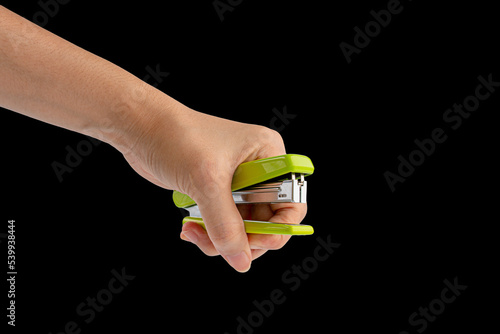 Hand and green stapler isolated on black background