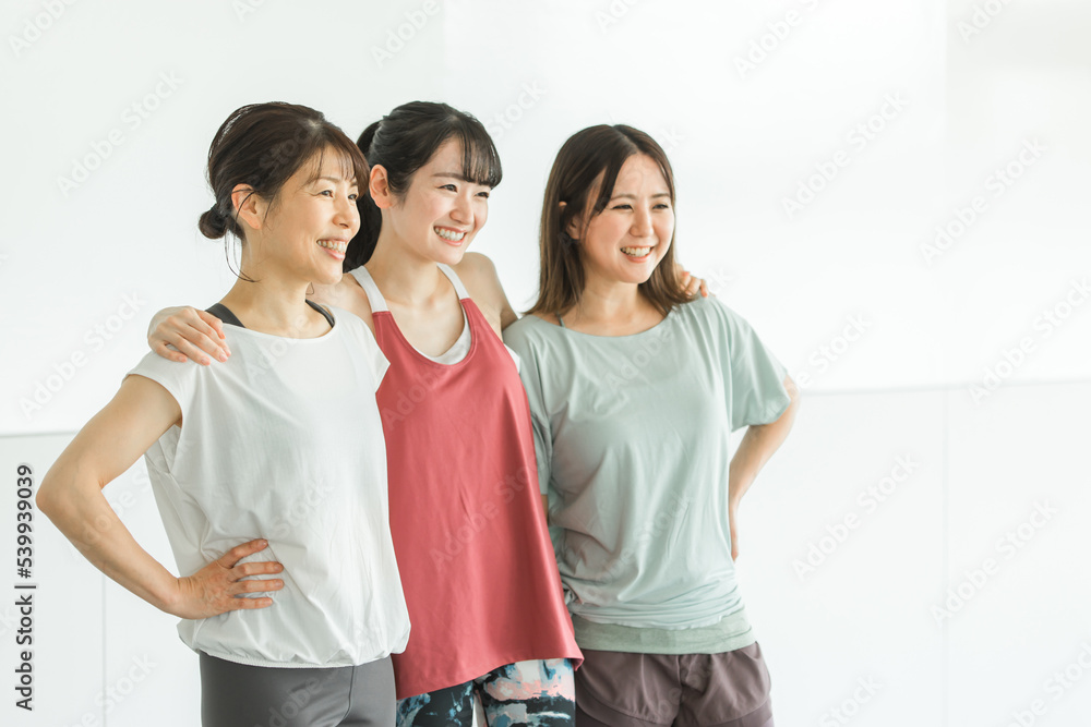 スポーツジムで肩を組むスポーツウェアのアジア人の女性達
