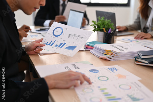 Cropped image of focused businessman analyzing statistics, financial graphs charts at meeting table