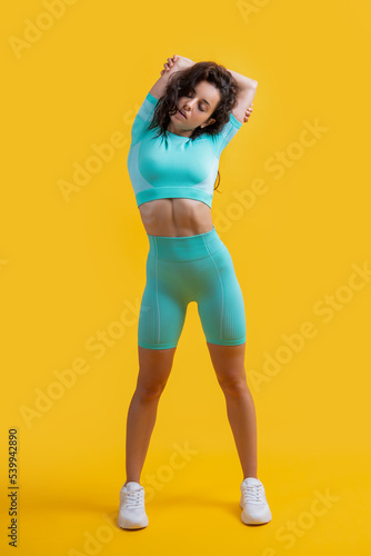 Fit woman doing overhead shoulder stretch exercise studio. Athletic girl exercising