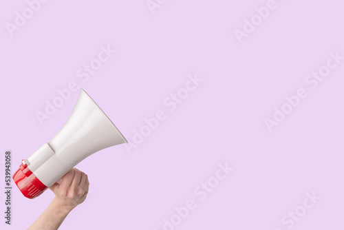 Megaphone in woman hands on a pink background.