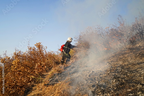 Almaty, Kazakhstan - 09.06.2022 : A firefighter makes his way to the place of ignition of dry grass and shrubs in the mountains.