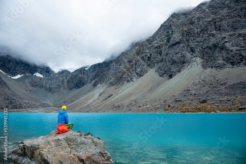 Woman enjoys Blaisvatnet, Blue lake is a polular hiking destination, with mountains of the Lyngen Alps, Lyngenfjord, Troms og Finnmark, Norway