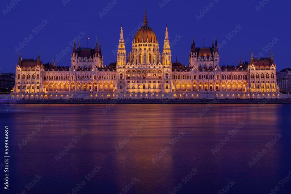 Budapeszt oświetlony budynek parlamentu Országház widziany z rzeki Dunaj po zachodzie słońca - obrazy, fototapety, plakaty 