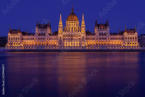 Budapeszt oświetlony budynek parlamentu Országház widziany z rzeki Dunaj po zachodzie słońca