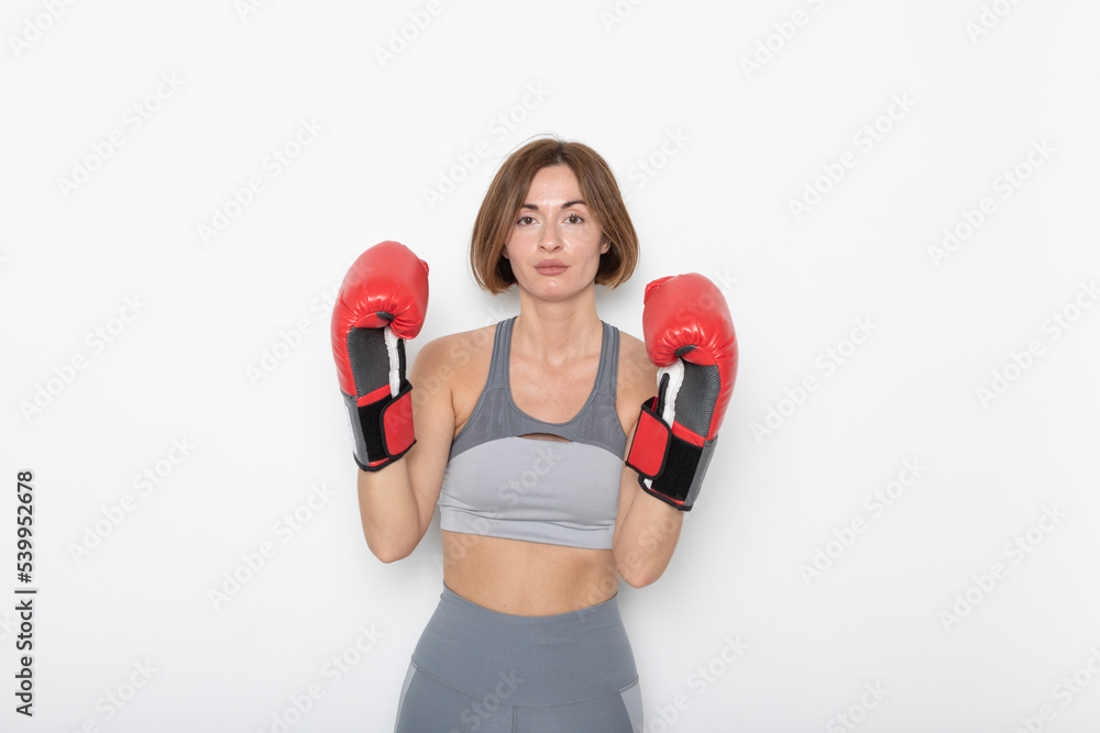 Young and attractive woman in boxing gloves posing isolated on white background