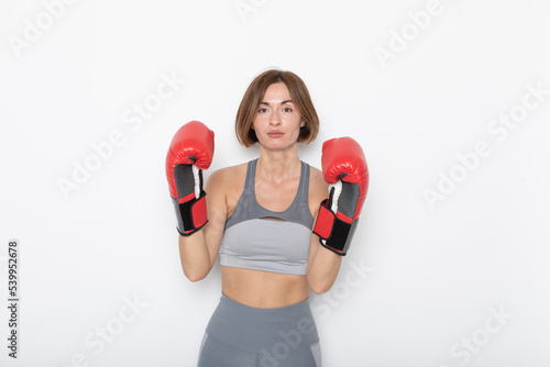 Young and attractive woman in boxing gloves posing isolated on white background