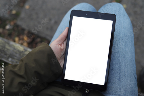 woman holds a tablet in her hands with a white, blank screen for design, copy space