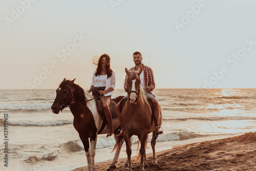 A loving couple in summer clothes riding a horse on a sandy beach at sunset. Sea and sunset in the background. Selective focus  © .shock