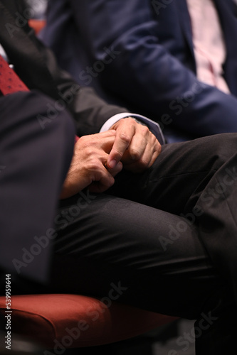 Hands with suit, rest on the legs the a person