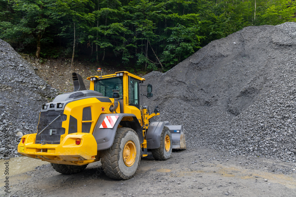 yellow digger with grey gravel for construction of the road